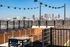 Chic rooftop patio with seating area, modern planters, and breathtaking skyline views under stylish string lights.