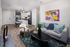 Modern open-concept apartment living room showcasing sleek kitchen island, contemporary furniture, and vibrant artwork.