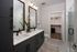 Elegant and modern bathroom with dual sinks, large mirrors, and a bright walk-in closet, featuring stylish black cabinetry and thoughtful decor.