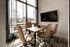 Bright and modern office space with sleek conference table, comfortable chairs, large window, and mounted TV, perfect for productive meetings.