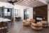 Modern open-concept lounge featuring comfortable seating, sleek wooden accents, and expansive windows offering stunning city views.