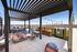 Modern rooftop terrace with stylish pergola and cozy seating, offering stunning cityscape views and a relaxed outdoor ambience.