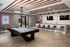 Chic recreation room with a sleek pool table, modern seating, and stylish ceiling lights, perfect for entertaining.
