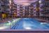 Luxurious apartment complex with a beautifully illuminated pool and stylish lounge chairs, perfect for relaxing evenings.