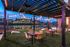 Charming outdoor patio with stylish seating under string lights, offering a serene riverside view at twilight.