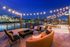 Enchanting outdoor terrace overlooking a vibrant cityscape, adorned with twinkling string lights and stylish seating, perfect for evening relaxation.