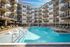 Luxurious apartment complex featuring a sparkling outdoor pool with modern poolside loungers and stylish balconies.