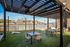 Charming riverside patio with modern pergola, sleek outdoor furniture, and vibrant city backdrop, perfect for relaxing.