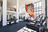 Modern fitness center with state-of-the-art equipment, vibrant mural, and floor-to-ceiling windows offering plenty of natural light.