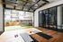 Versatile indoor-outdoor workout space with floor-to-ceiling windows, exercise mats, and a view of greenery and modern apartments.