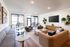 Elegant and spacious living room with modern decor, featuring a large sofa and armchairs, stylish coffee tables, and wall-mounted greenery, illuminated by natural light through floor-to-ceiling windows.