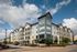 Contemporary apartment complex with modern architecture, lush landscaping, and ample parking under a vibrant sky.