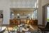 Inviting workspace adorned with stone wall, modern lighting, and stylish brown chairs, offering a blend of comfort and aesthetics amidst natural light and greenery.