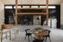 Chic modern cafe interior featuring a stylish wooden beam design, elegant black pendant lighting, and a cozy seating area with lush greenery and minimalist decor.
