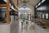 Modern open-concept cafe with high ceilings, elegant chandeliers, and ample natural light streaming through large windows, featuring stylish wooden accents and comfortable seating areas.