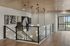 Elegant hallway interior with modern pendant lights and artistic wall decor, featuring glass railing and wooden flooring.