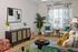 Chic and inviting living room with stylish decor, featuring patterned chairs, a modern black console, and vibrant greenery for an elegant touch.
