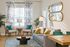 Chic and inviting living room with modern decor, featuring a comfortable gray sofa, stylish armchairs, vibrant cushions, and elegant mirrors, accented with leafy curtains for a fresh ambiance.