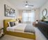 Elegant bedroom featuring a cushioned yellow bed frame, modern art, and abundant natural light through large windows.