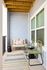 Charming apartment balcony with cozy seating and colorful outdoor rug, ideal for relaxation.