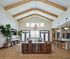 Elegant open-concept living space featuring high ceilings with wooden beams, a stylish lounge area, and a modern kitchen with bar seating.