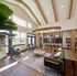 Bright and inviting living space with vaulted ceilings, stylish wooden beams, and natural light illuminating a cozy seating area and modern kitchen with bar seating.