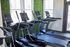 Modern fitness center featuring state-of-the-art treadmills with a vibrant green hedge wall backdrop.