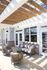 Charming outdoor patio with elegant wicker furniture under a stylish wooden pergola.
