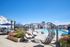 Luxurious apartment complex featuring a large outdoor pool, stylish lounge chairs, and modern patio furniture under bright blue skies.