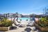 Luxurious community pool area with elegant hanging chairs, sun loungers, and beautifully landscaped surroundings.
