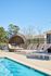 Inviting outdoor pool area with stylish wicker pod seating and modern lounge chairs, perfect for relaxation under a clear blue sky.