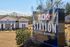 Inviting entrance to Station at Lake Murray apartment homes, featuring a charming building with a well-manicured landscape under a bright, sunny sky.