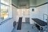 Modern pet grooming salon with stylish tile walls, equipped wash station, and grooming table, complemented by a bright window view.