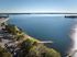 Breathtaking aerial view of a serene lakeside landscape with lush greenery and expansive water under a clear blue sky.