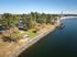 Scenic aerial view of a lush green park by a serene lake, featuring cozy picnic shelters and a charming dock, perfect for outdoor relaxation.