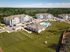 Beautiful aerial view of modern apartment complex with spacious green lawns and a refreshing swimming pool, surrounded by serene natural landscapes.