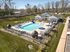 Inviting outdoor pool area with sun loungers and umbrellas, complemented by a charming clubhouse and lush surroundings.