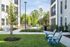 Charming apartment courtyard with lush greenery, outdoor seating, and convenient grills for a relaxing community atmosphere.