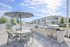 Charming outdoor patio with a modern grill station, stylish umbrella, and dining set in a beautiful suburban setting.