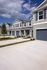 Modern townhouses with elegant gray facades and well-maintained lawns under a clear blue sky.