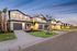 Charming row of modern suburban homes at dusk, featuring well-manicured lawns and inviting warm lights.
