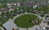 Vibrant community courtyard surrounded by modern apartment buildings, featuring a spacious green lawn, outdoor seating, and a cozy pergola area.