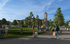 Vibrant community park with lush greenery, families enjoying a sunny day, and cozy seating areas under festive string lights.
