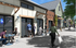 Charming streetscape with people enjoying a caf&eacute;-style outdoor seating area in front of stylish, modern buildings.