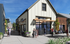 Charming community plaza with modern buildings, lush greenery, and people enjoying leisure time under a clear blue sky.