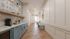 Chic apartment hallway with elegant patterned tiles, modern lighting, and a convenient coffee station on light wood flooring.