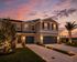 Beautiful two-story townhouse with a double garage, illuminated at sunset, featuring manicured lawns and palm trees in a serene neighborhood setting.