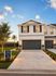 Charming suburban duplex with modern garage doors, lush landscaping, and a welcoming atmosphere. Ideal home in a serene neighborhood with an 'Now Leasing' sign inviting new residents.