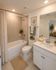 Elegant bathroom with modern amenities, featuring a soothing bathtub, stylish vanity, and warm lighting for a luxurious feel.