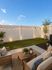 Charming outdoor patio with cozy seating, wooden coffee table, and ambient string lights, perfect for evening relaxation.